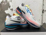 Pair of white Nike basketball shoes shown from the side, with blue, coral, and yellow accents.
