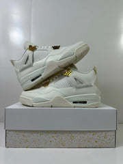 Pair of white Jordan 4 sneakers stacked on a box, showing the side panels, gold accents, and outsole edge.