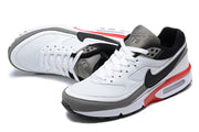 Angled top view of white and grey Nike Air Max sneakers with black accents and red heel details.