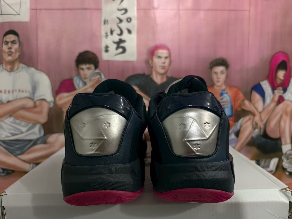 Rear view of black basketball shoes with silver heel panels and pink outsoles.