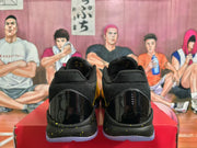 Rear view of yellow and black sneakers showing glossy black heel panels, black collars, speckled midsoles, and translucent outsoles.