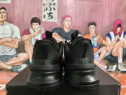 Rear view of a pair of black Nike basketball sneakers displayed on a black shoebox.