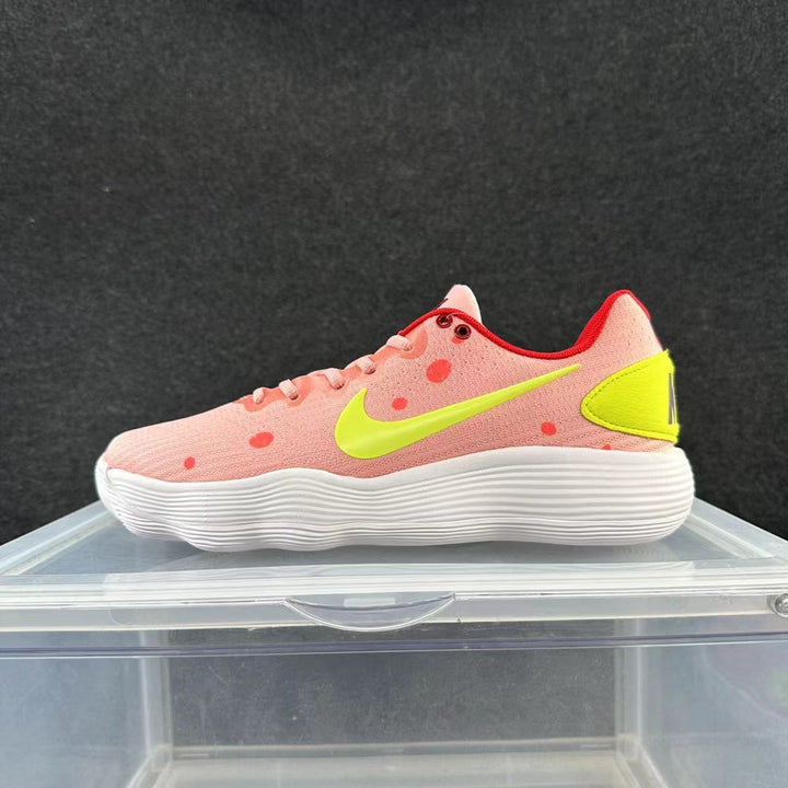 Side view of a pink low-top Nike sneaker with red dot accents, a bright yellow Swoosh and heel panel, and a white ridged sole