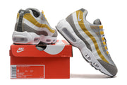 Nike Air Max 95 TT sneakers in grey, white and yellow beside a box labeled DM0011-010; the box shows size 8.
