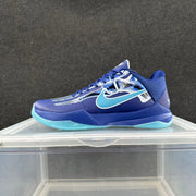 Side view of a blue low-top basketball shoe with skull graphic, turquoise Swoosh, and turquoise outsole