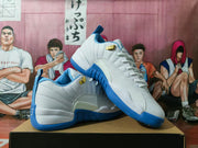 Angled view of white and blue Jordan sneakers with blue outsoles, white laces, and gold-tone lace hardware.