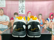 Rear view showing the black heel panels, white midsoles, gold collar accents, and signature-style graphics.