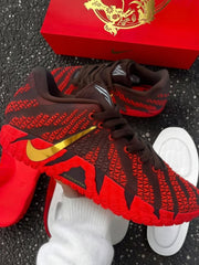 Brown and red Nike basketball sneakers with gold Swoosh branding beside a red horse-themed box.