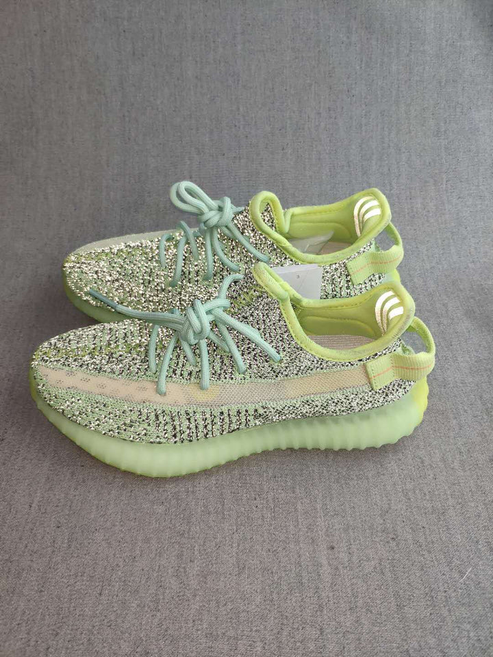 Pair of green and black patterned Yeezy 350 V2 sneakers shown from above on a gray background.