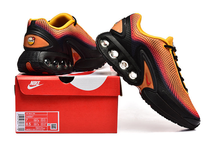 Nike Air Max DN sneakers in orange, pink, yellow, and black shown with a branded shoe box.
