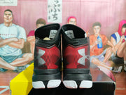Rear view of the black and red basketball sneakers showing the red-striped heel panels, Under Armour branding, and white outsole sections.