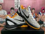Angled view of the pair showing the textured uppers, black side branding, gold-orange collars and outsoles, and black heel sections.