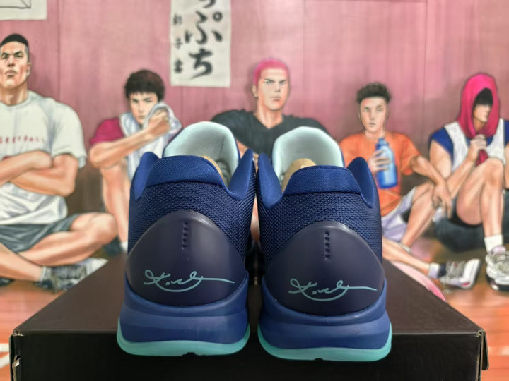 Rear view of navy blue basketball shoes with Kobe branding on the heels and translucent aqua outsoles.
