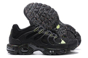 Side and outsole views of black Nike Air Max Plus sneakers with speckled soles