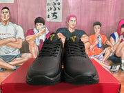 Front view of black basketball sneakers with perforated toes, black laces, and gold tongue emblems.
