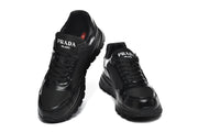 Front view of a pair of black lace-up sneakers with logo text on the tongues