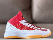 Side profile of a red and white high-top basketball shoe with gold accents and a gum-colored outsole.