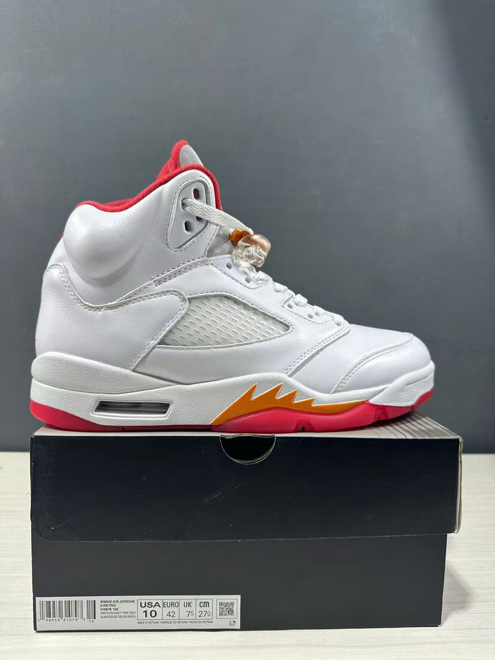White Jordan high-top sneaker with red and orange accents displayed on a black shoe box; the box label shows USA 10, EUR 44, UK 9 and CM 28.