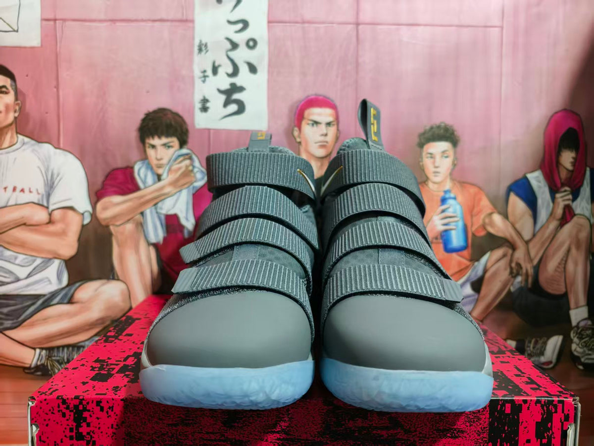 Front view of grey Nike high-top basketball shoes with multiple straps and pale blue outsoles.