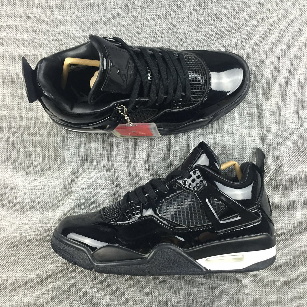 Pair of black Air Jordan 4 high-top sneakers shown from above and the side on a gray fabric surface.