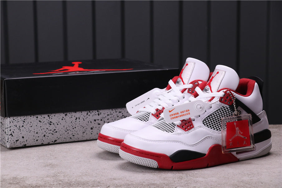Pair of white, red, and black Jordan 4 Retro sneakers displayed with a Jordan shoebox.