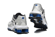 Rear and outsole views of silver Nike Shox Ride 2 sneakers with blue cushioning columns.