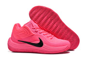 Side and outsole view of a pink Nike basketball sneaker showing the black Swoosh and wavy traction pattern.