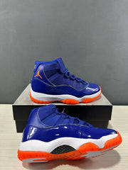 Side and outsole view of blue high-top sneakers showing glossy blue overlays, a white midsole, and orange traction sections.