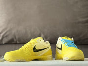 Front-facing view of the yellow and cream basketball sneakers, including one shoe with blue laces.