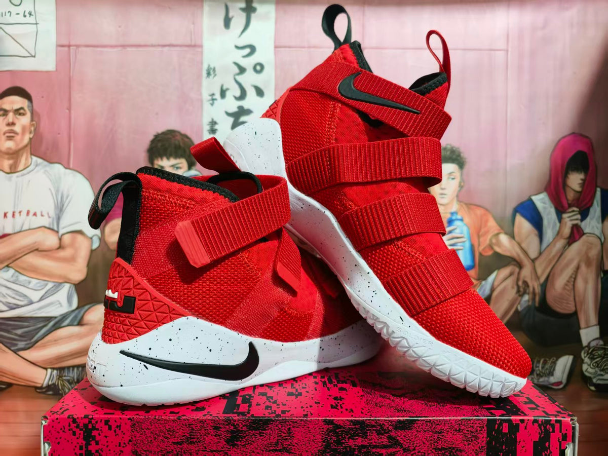 Red and black Nike LeBron basketball shoes with multiple straps and a white speckled sole