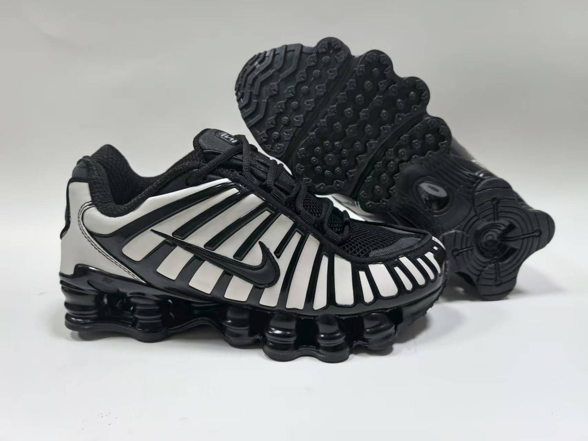 Black and white Nike Shox TL-style sneaker shown from the side, with a second shoe displaying the podded outsole.