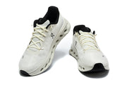Pair of white On Cloudmonster 3 sneakers viewed from the front and side.