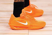 Bright orange Nike GT 3.5 basketball shoes with white Swooshes, shown on court.