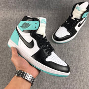 Handheld angled view of one sneaker showing the black toe overlay, white perforated toe box, and mint green outsole edge.