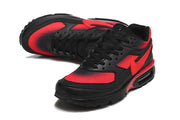 Angled view of black and red Nike Air Max sneakers with lace-up closure.