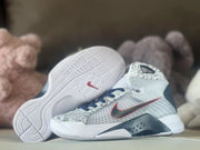 Basketball shoe side view with the outsole visible, patterned upper, and navy-red details