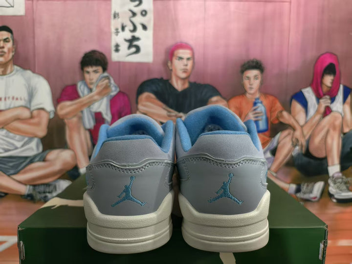 Rear view of blue and gray low-top sneakers showing the heel logos and layered off-white soles.
