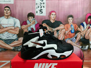 Side view of a black Nike sneaker with white sculpted panels, orange accents, and a visible Swoosh.