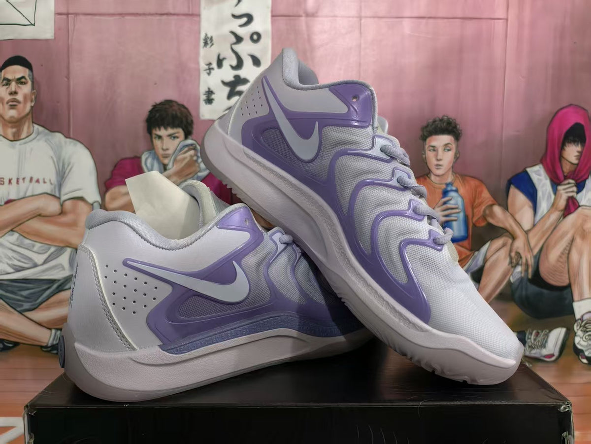 Pair of light gray and lavender Nike Team Dancer sneakers shown from the side