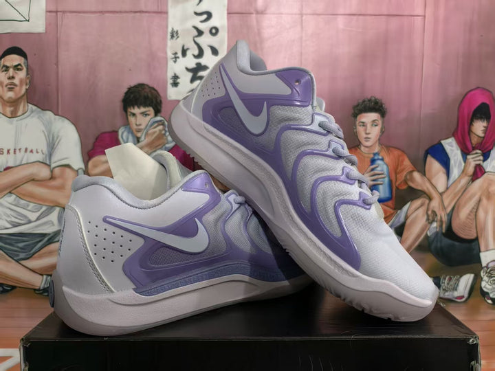 Pair of light gray and lavender Nike Team Dancer sneakers shown from the side