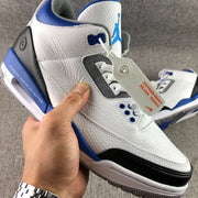 Close-up side view showing the textured white upper, perforated gray lace panel, blue eyelets, and black toe overlay.