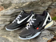 Angled view of the black and white sneaker pair showing textured uppers, glossy overlays, red accent tabs, and white heel panels.