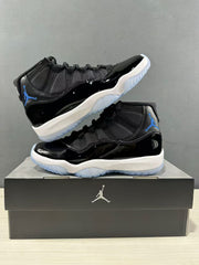 Two black and blue high-top sneakers arranged on a black shoe box in an angled product display.