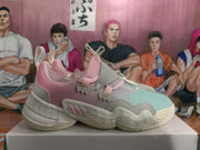 Side view of a pink and light grey Adidas basketball-style sneaker showing layered panels, lace closures and a sculpted off-white sole.