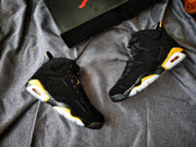 Pair of black and gold Jordan Air Jordan 6 sneakers shown from angled top and side views beside a shoe box.