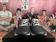 Front view of black textured basketball shoes with white laces and red tongue emblems.