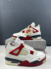 Close three-quarter view of the white and red sneakers showing the lace area, mesh panels, and molded side wings.