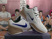 Three-quarter view of the white basketball sneakers with blue side branding, tan heel panels, and speckled midsoles.