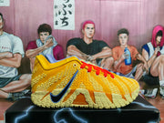 Side view of a yellow Nike LeBron 12 basketball shoe with red laces, blue Swoosh, and textured outsole.