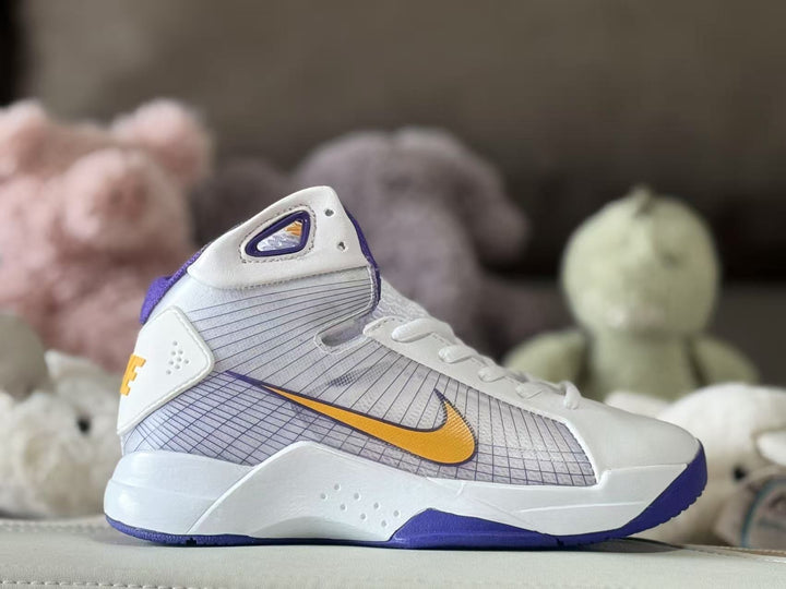 Side view of a white Nike kids’ high-top sneaker with purple trim, a gold Swoosh, and a patterned side panel.